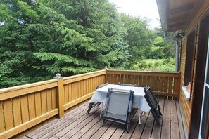 Eine Holzterrasse mit Tisch und Stühlen, umgeben von dichtem Grün.