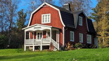 A red wooden house with a white porch and a sign reading 'SKOGSBORG'.