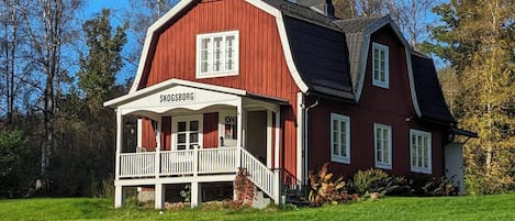 A red wooden house with a white porch and a sign reading 'SKOGSBORG'.