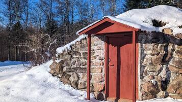 A stone building with a red door and a small overhang.