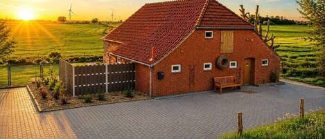 A brick house with a sloped roof, a wooden bench, and a paved driveway.