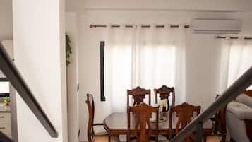 A staircase leading to a dining area with wooden chairs and a chandelier.