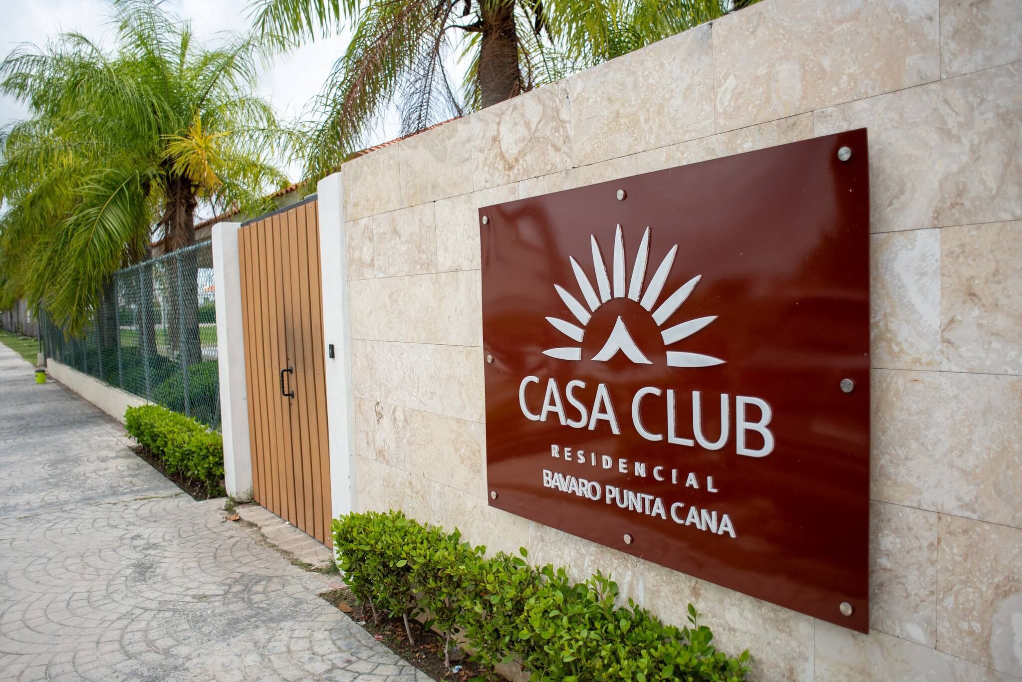 Ein Schild mit der Aufschrift 'CASA CLUB RESIDENCIAL BAVARO PUNTA CANA' inklusive Logo, angebracht an einer wandförmigen Fläche mit Fliesen.