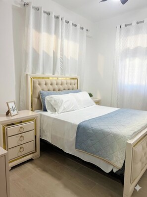 Ein Schlafzimmer mit einem Bett, Nachttischen und Vorhängen.