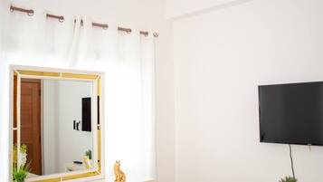 Ein Schlafzimmer mit Bett, Deckenventilator, Fernseher, Kommode und Spiegel.
