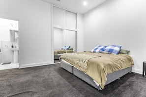 A modern bedroom with a bed, a wardrobe, and a bathroom. - Large Waterfront Stay by Britomart & Harbour (Auckland city)
