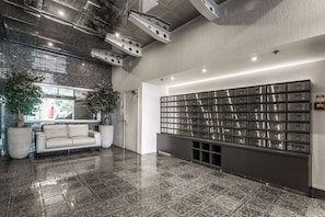 Eine Lobby mit einer Couch, einer großen Wand mit Briefschlitzen und einem Fliesenboden.