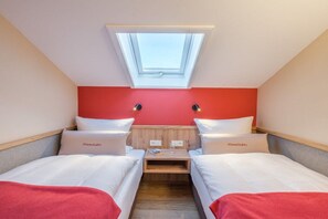 A compact room with two beds, a skylight, and a red accent wall. - Holiday apartment in Oberstdorf with Wi-Fi (Oberstdorf)