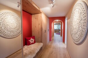 A hallway with a wooden bench, a red pillow, and decorative wall panels. - Holiday apartment in Oberstdorf with Wi-Fi (Oberstdorf)