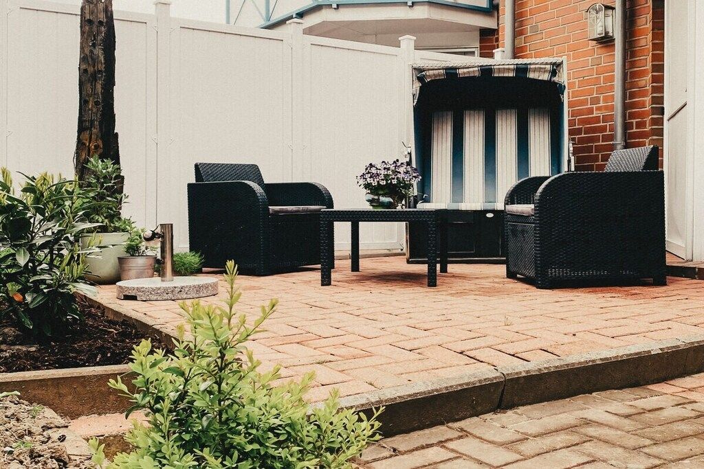 Une terrasse avec des meubles en osier, une table et des plantes en pot.