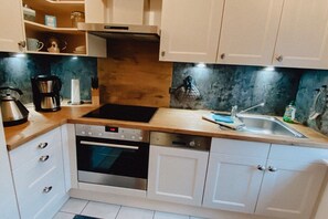 Eine moderne Küche mit weißen Schränken, einem eingebauten Backofen, einer Spülmaschine und einer Kaffeemaschine.