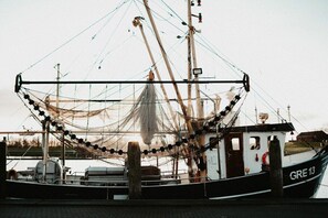 Ein Fischerboot liegt an einem Steg, darüber ein Fischernetz.