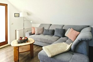 Una sala de estar con un sofá gris, una mesita de madera y una lámpara de pie.