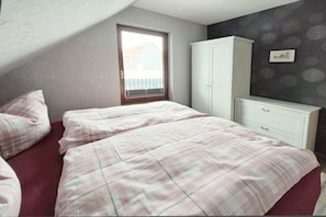 Ein Schlafzimmer mit Bett, Kleiderschrank und Fenster.