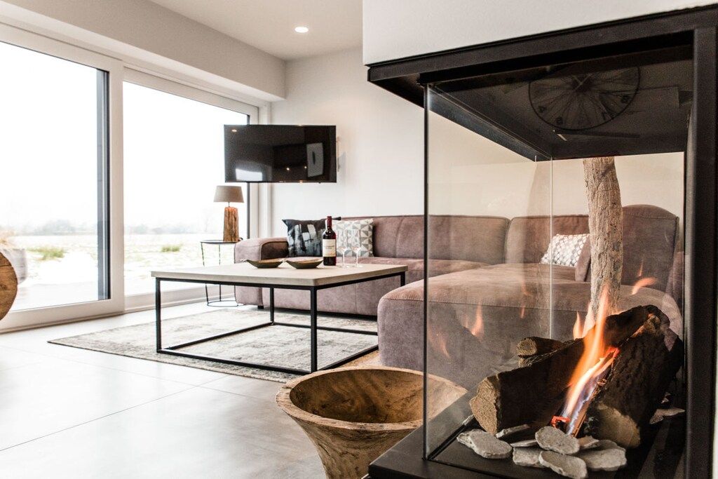 Una sala de estar moderna con chimenea, un sofá, una mesa de centro y un televisor montado en la pared.