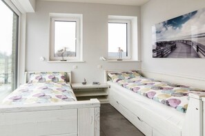 Ein Schlafzimmer mit zwei Betten, einem Schreibtisch und einem großen Fenster.