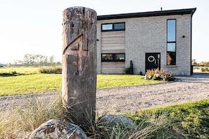 Ein modernes Haus mit Backsteinfassade, einer Garagentür und einem Holzpfosten mit Metallriegel.