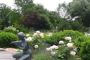 A garden with a statue, lush greenery, and flowering plants. - Holiday apartment in Trebel with barbecue (Trebel)