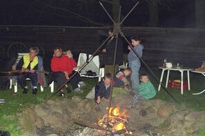 A group of people gathered around a campfire with a rustic outdoor setting. - Holiday apartment in Trebel with barbecue (Trebel)