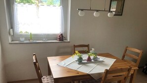 A dining area with a wooden table, four chairs, and a window with a view. - Holiday apartment with 1 bedroom (Traben-Trarbach)