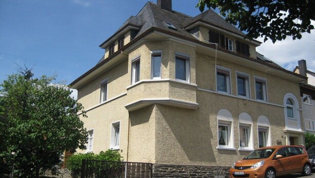 A two-story house with a stone facade, multiple windows, and a parked car in front. - Holiday apartment with 1 bedroom (Traben-Trarbach)