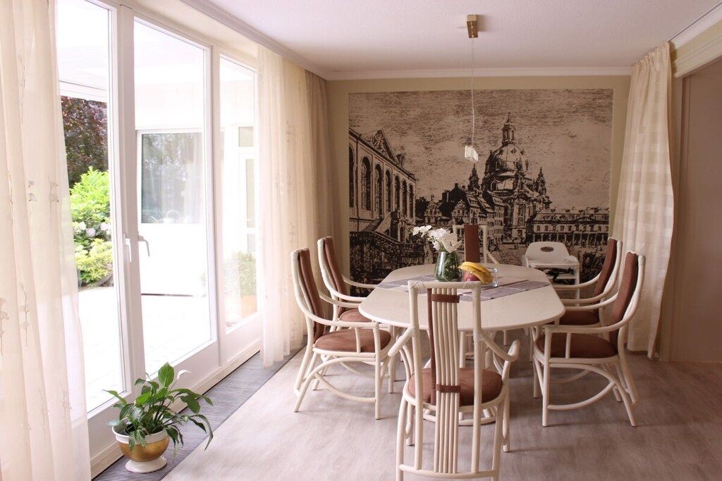 A dining area with a round table, white chairs, and a mural on the wall.