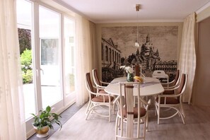 Ein Essbereich mit einem runden Tisch, weißen Stühlen und einem Wandgemälde.