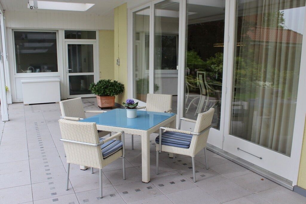 A patio with a table and chairs, a potted plant, and a sliding glass door.