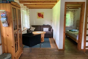 A cozy room with a wooden cabinet, a sofa, a round table, and a bed. - Holiday home with 1 bedroom (Berge OT Börstel)