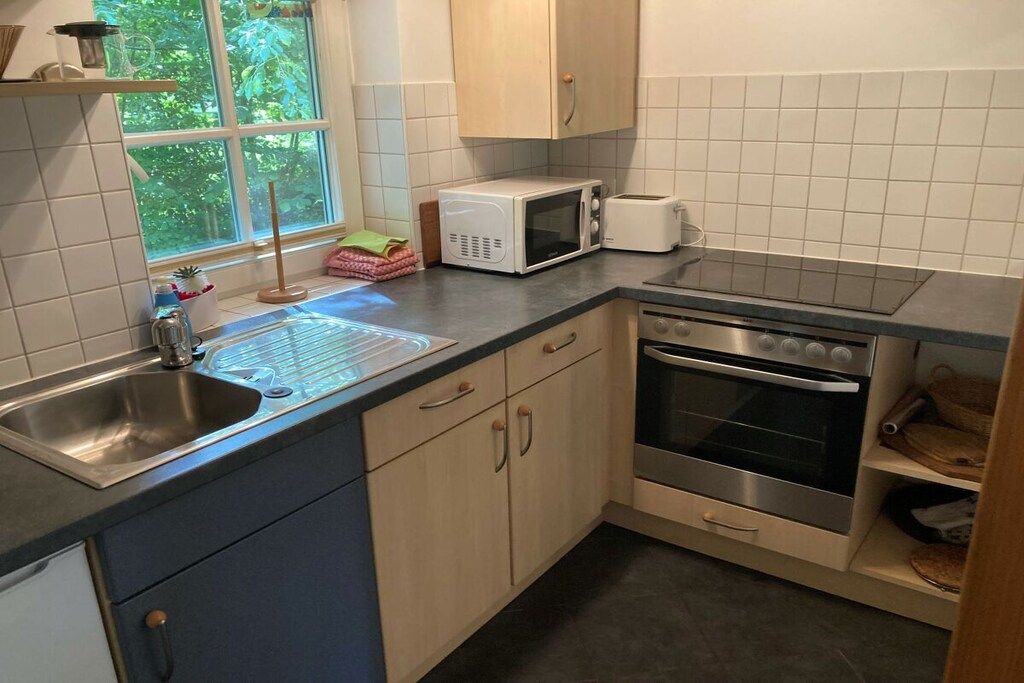 Een kleine keuken met een spoelbak, magnetron, broodrooster en oven.