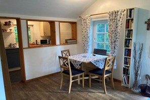A dining area with a table, chairs, a laptop, and a bookshelf. - Holiday home with 1 bedroom (Berge OT Börstel)