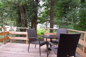 Eine Holzterrasse mit Korbmöbeln und Blick auf ein bewaldetes Gebiet.