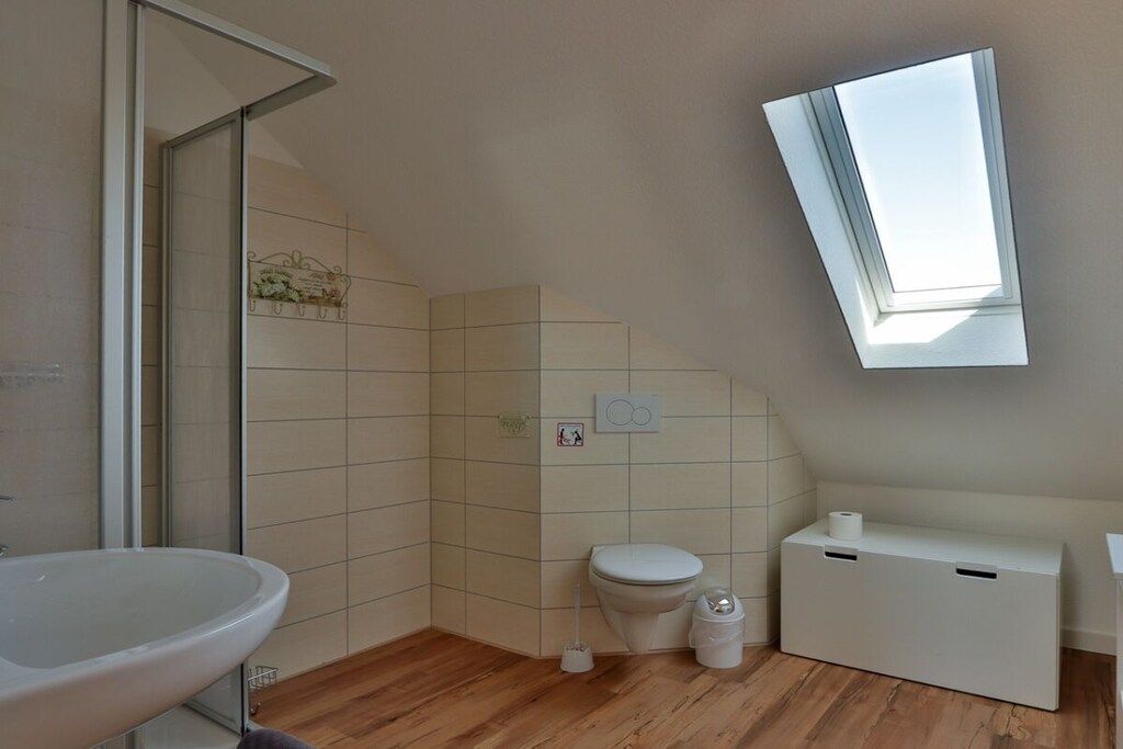 A modern bathroom with a freestanding bathtub, a toilet, and a bidet. There is a skylight above the toilet.