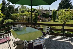 An outdoor patio with a table and chairs, a grill, and a wooden fence. - Holiday home in Arendsee with swimming pool (Arendsee)