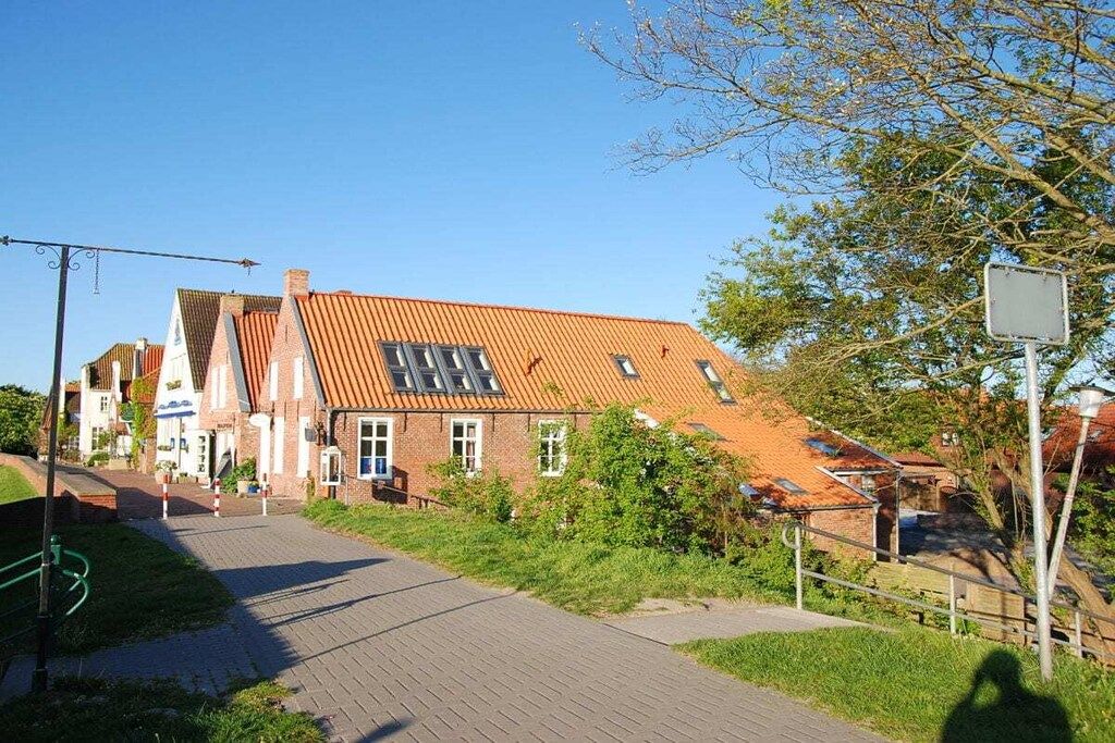 En byggnad med ett sluttande tak, en asfalterad gångväg som leder fram till den och en klar himmel.