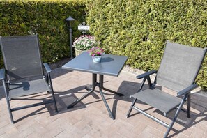Zwei Gartenstühle und ein Tisch mit einem Blumentopf.