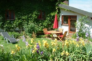 Ein Garten mit Tisch und Stühlen, umgeben von blühenden Pflanzen.