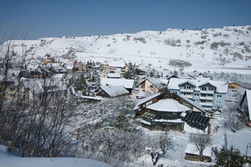 Un pueblo cubierto de nieve con casas de madera tradicionales y un edificio moderno con paneles solares.