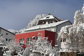 A red building with a sloped roof, surrounded by snow-covered trees and a clear sky. - Holiday apartment with 2 bedrooms (Waldshut-Tiengen)
