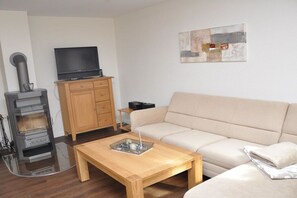 Un salon avec un canapé, une table basse, un téléviseur posé sur un meuble et une cheminée.