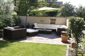Un área de patio exterior con un conjunto de sofás, una mesa de centro y una planta en maceta.