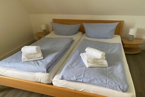 Ein Doppelbett mit zwei Kissen, ein gefaltetes Handtuch und ein Nachttisch mit Lampe.