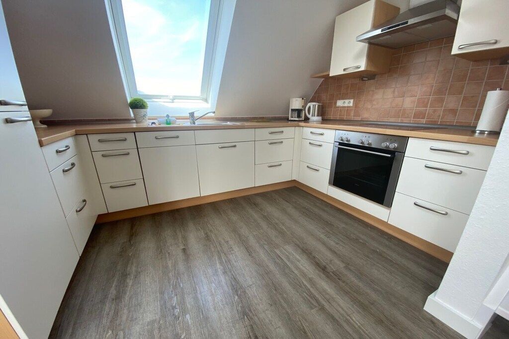 A kitchen with white cabinets, a built-in oven, and a window above the sink.