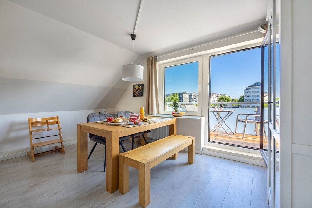 Un appartement moderne doté d’un coin repas comprenant une table en bois, un banc et des chaises.