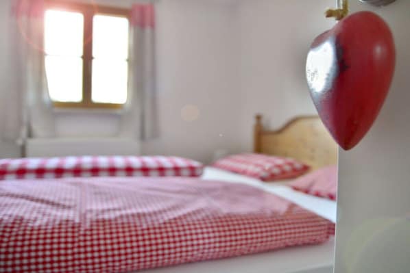 A bedroom with a checkered bedspread, a wooden headboard, and a window with curtains.