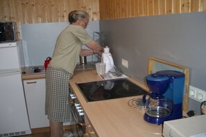 A person in a kitchen with a microwave, stove, coffee maker, and a small refrigerator. - Holiday apartment with 1 bedroom (Wegscheid)