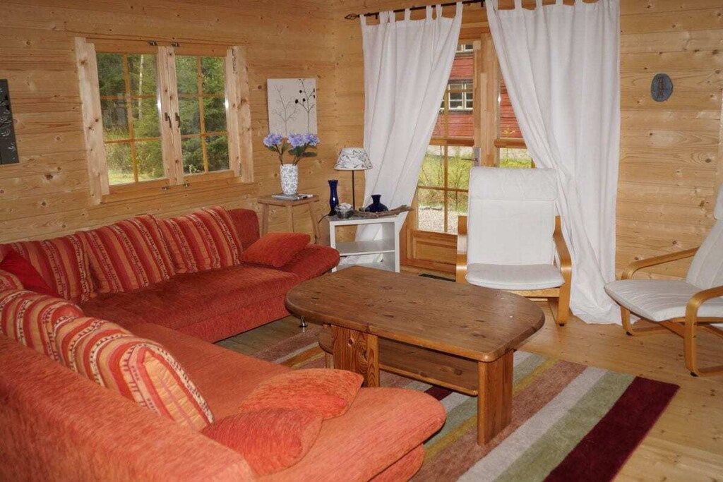 Un interior de cabaña acogedor con un sofá, una mesa de madera y una silla.