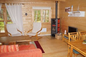 A cozy cabin interior with a fireplace, wooden furniture, and a television. - Holiday home in Lur with swimming pool (Lur)