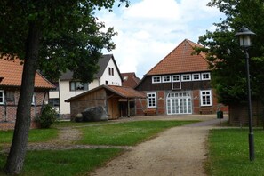 A rural building with a dirt path leading to a wooden door, surrounded by trees and a clear sky. - Holiday home with 1 bedroom (Visselhövede)