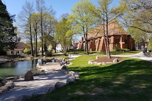 A park with a pond, a brick building, and a pathway. - Holiday home with 1 bedroom (Visselhövede)